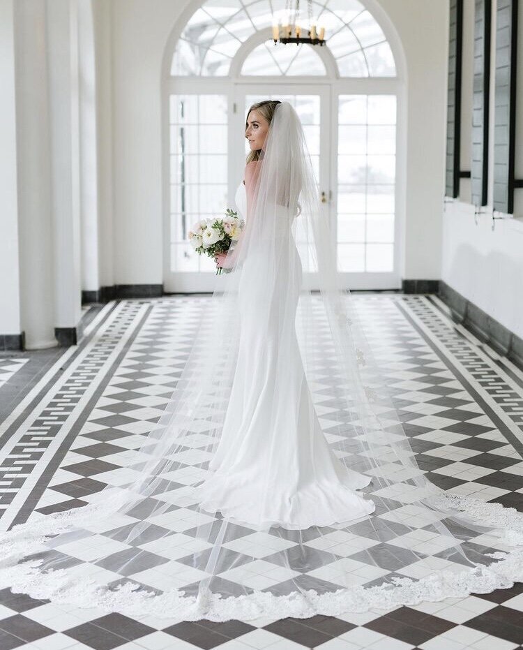 Full body bridal portrait at Casa Loma wearing a long veil and with her bouquet