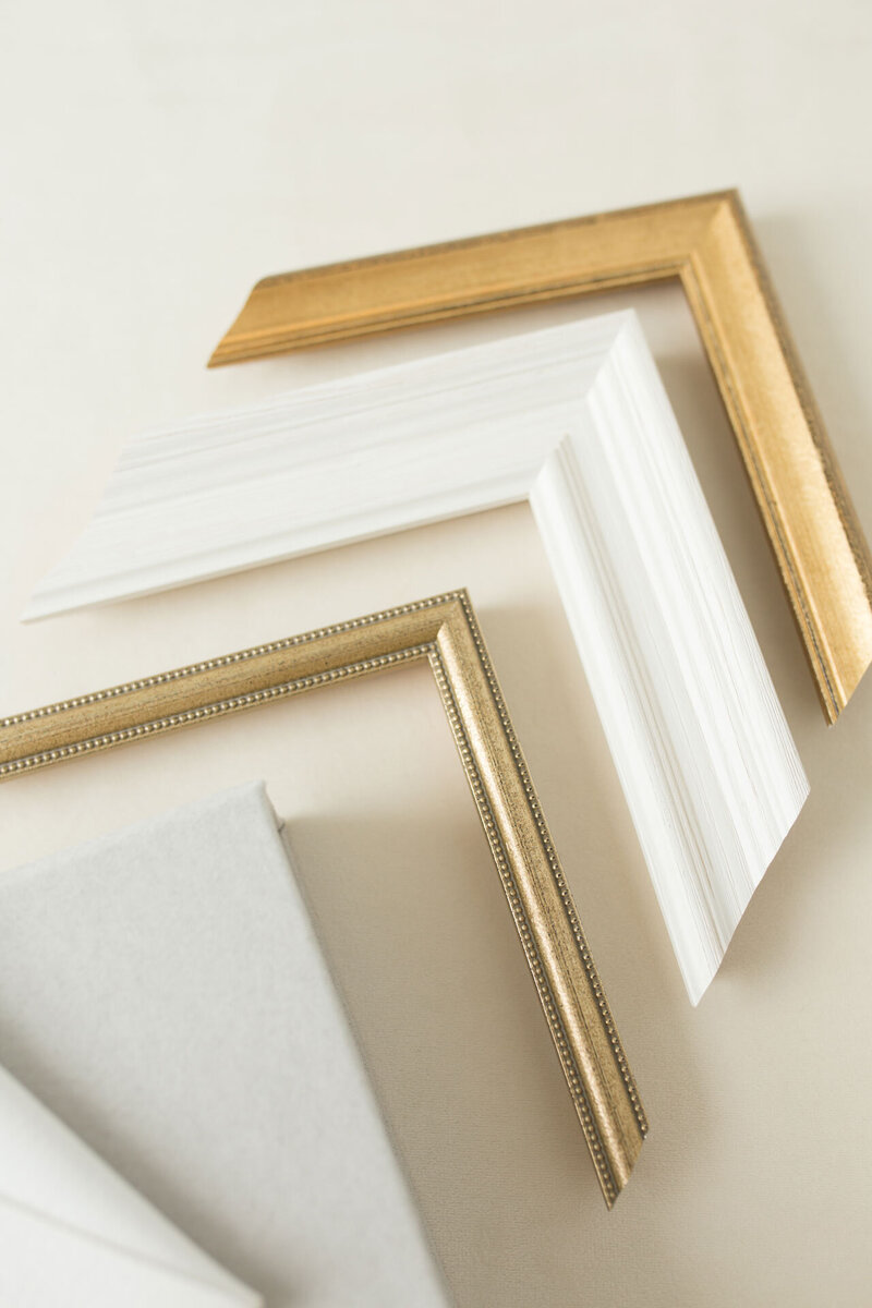 Eckstücke weißer und goldener Bilderrahmen gereiht an eine weiße Leinwand.