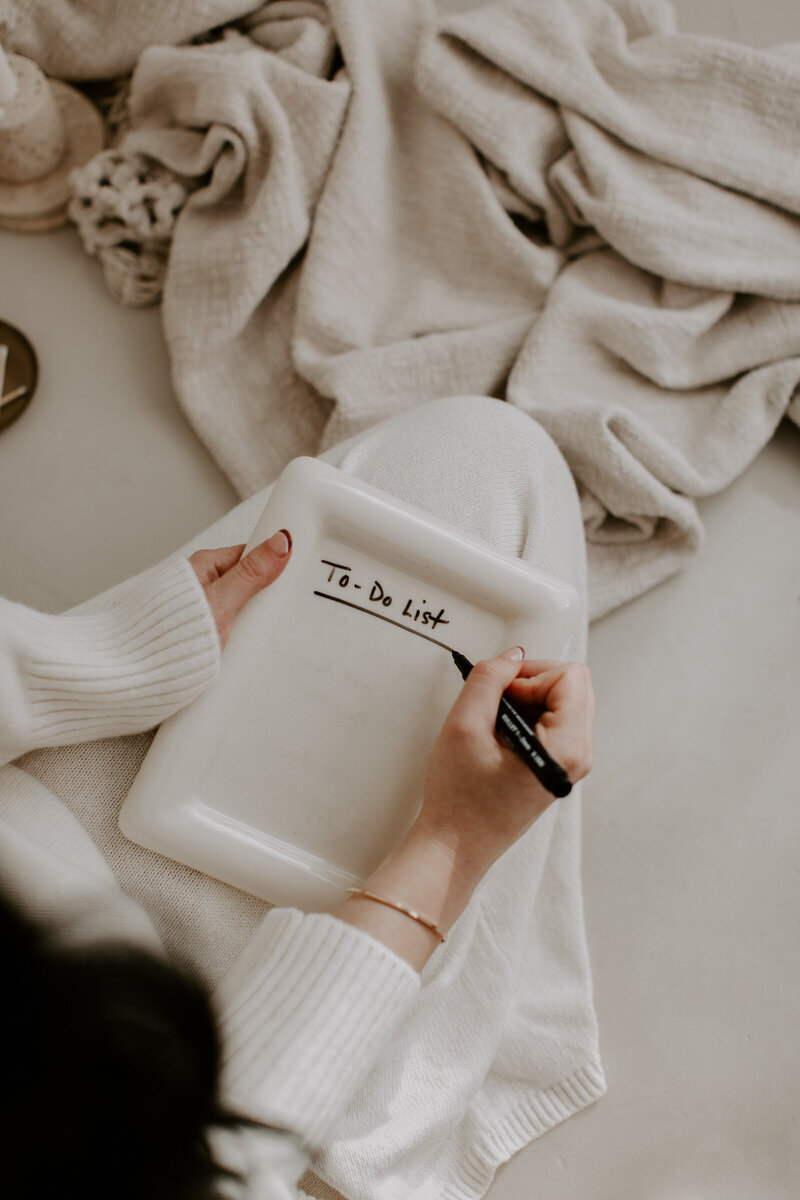 Woman writing a to-do list on a white frame