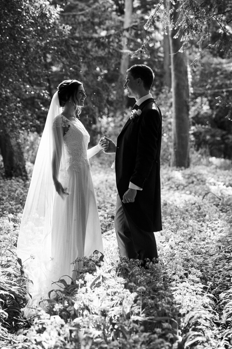 Black and white photo of bride and groom in wooded forest