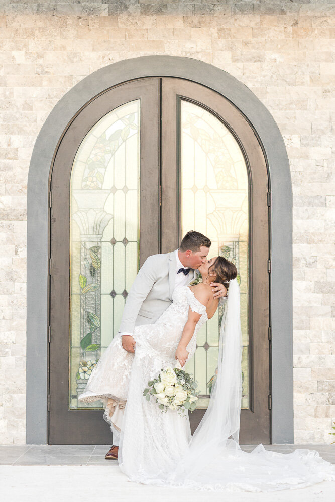 bride and groom kissing in front of wedding venue