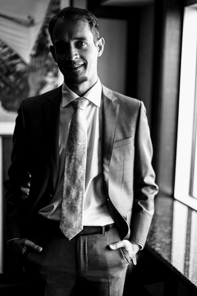 Solo portrait of groom smiling at the camera with his hands in  his pocket