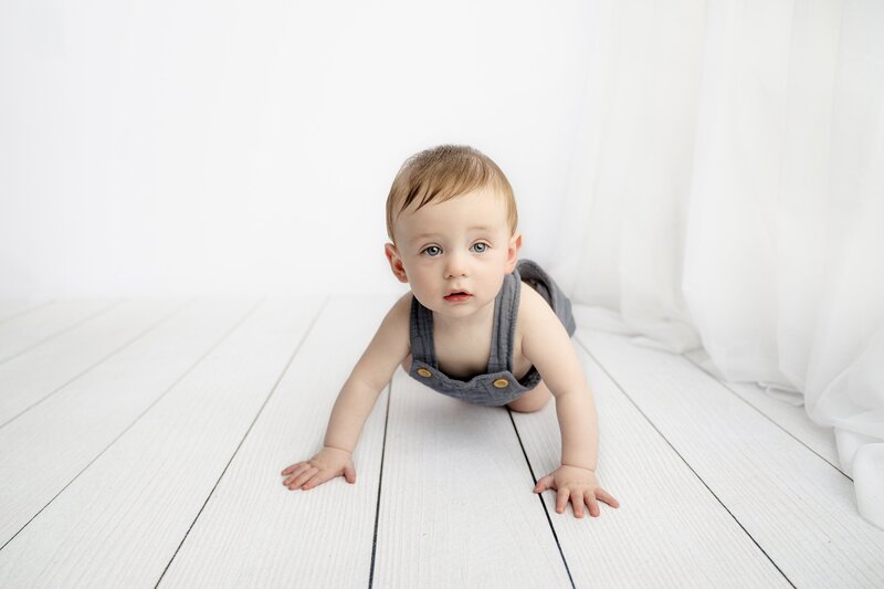 7 month old crawling  in blue overalls