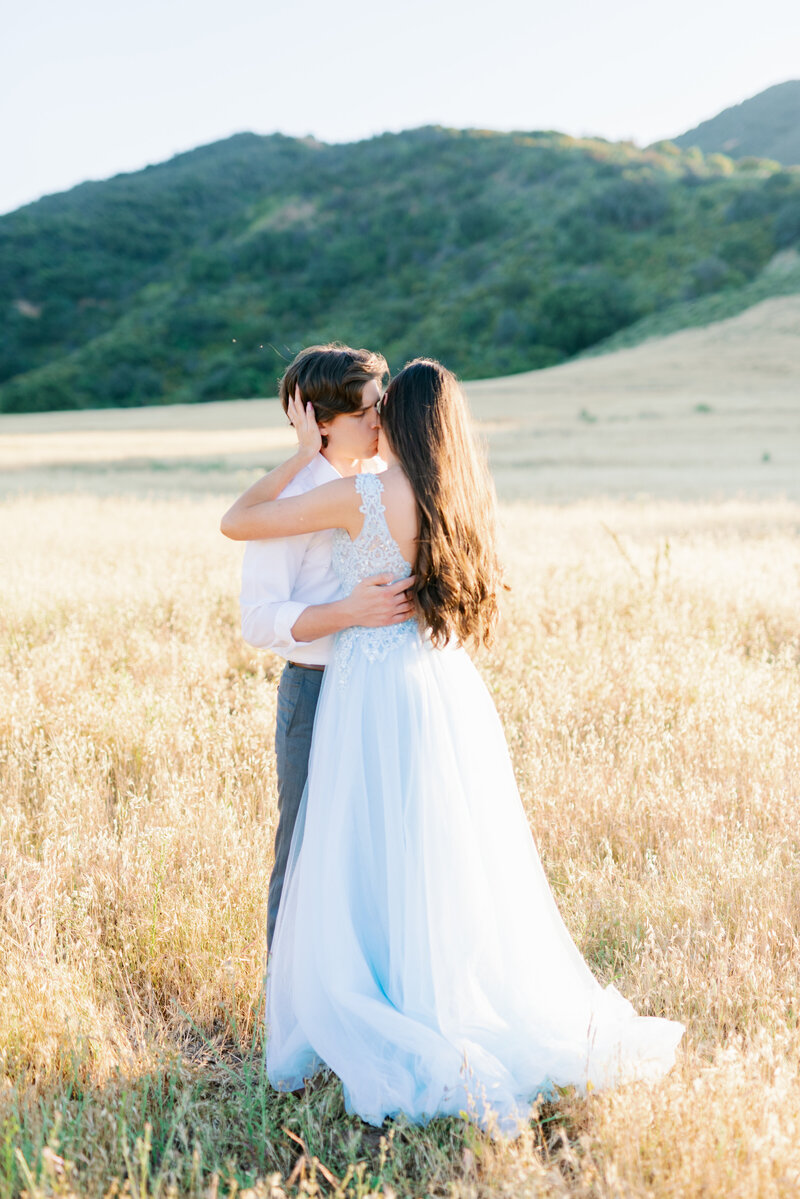 fancy engagement photo with long blue dress in a golden field location