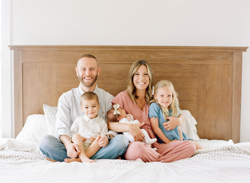 Family of 5 sitting on the bed for a portrait during their newborn session in Raleigh NC. Photographed by Raleigh newborn photographers A.J. Dunlap Photography.