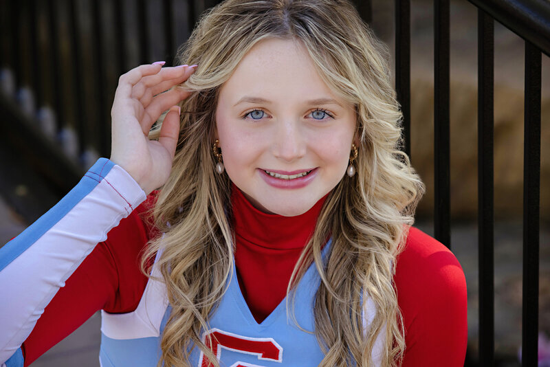 Charlotte Catholic HS Cheerleader sitting in front of a black metal railing and looking straight into the camera in Charlotte NC