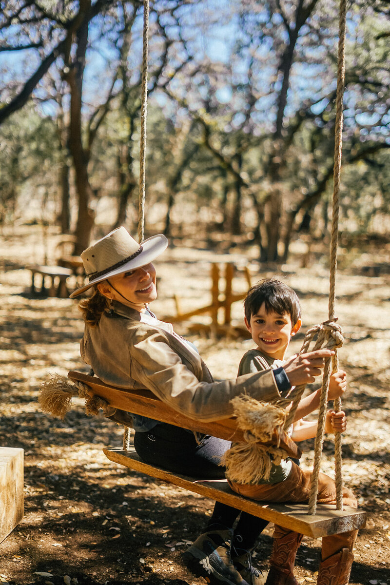 Woman and young boy on a wooden swing outside