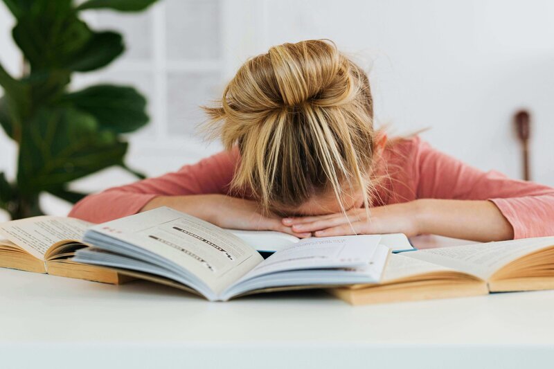 Student avoiding work with a book over her face