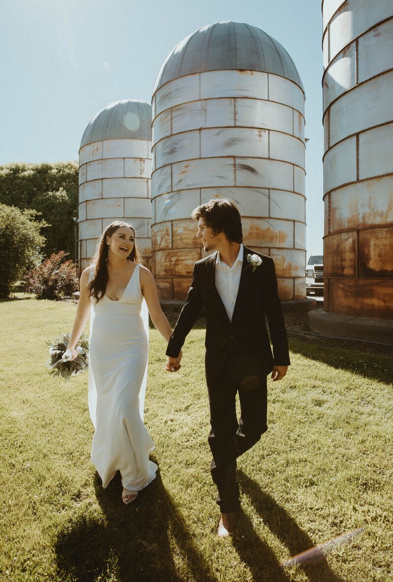 Couple Walking with Vintage Silos in the Background - Jillian & Cody | Shadow Lake Ranch Vintage Inspired Wedding Prosser Washington
