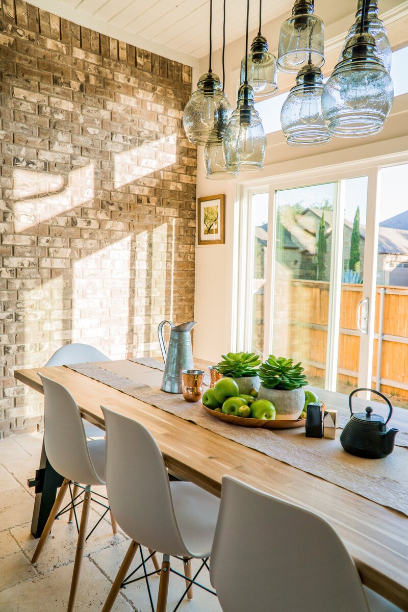 light filled dining room with brick wall and floor to ceiling windows