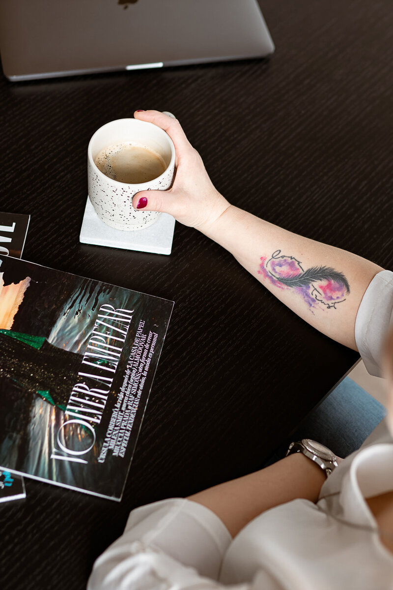 holding coffee cup surrounded by magazines