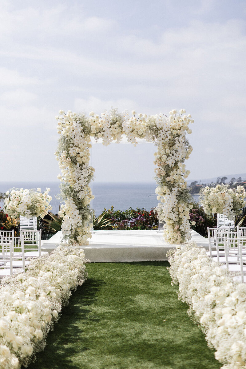 grand and elegant all white flowers wedding alter on top of a cliff overlooking the ocean