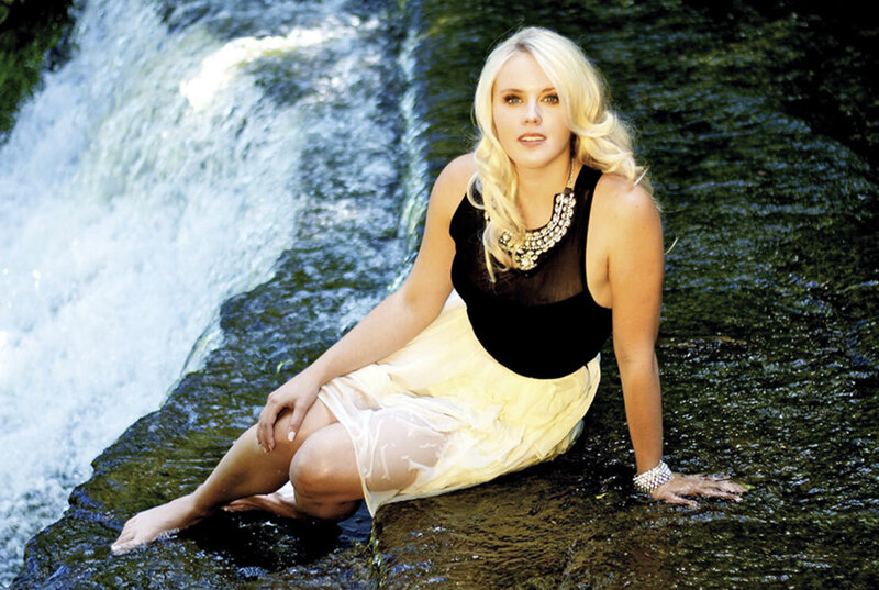 Female musician portrait Jrista Earle sitting at edge of waterfall