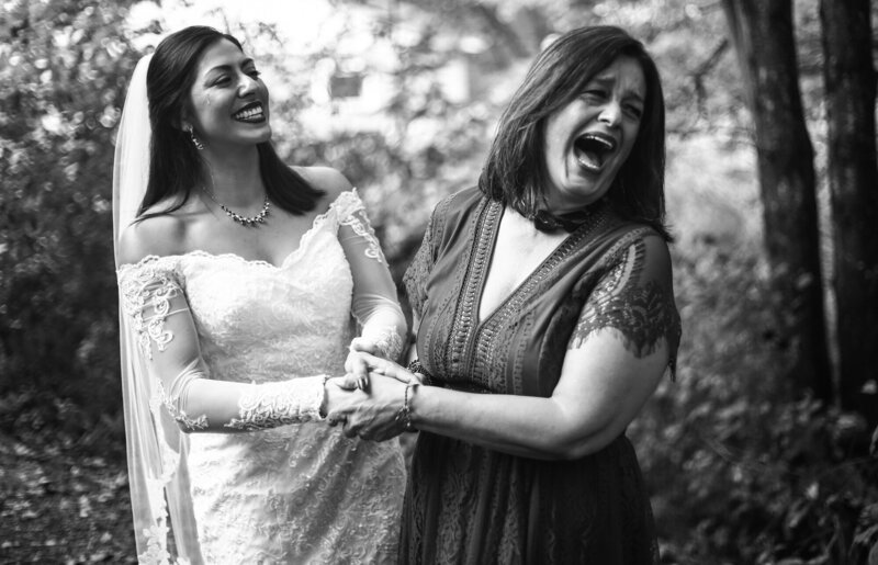 Bride and her stepmpther leaning back and laughing before wedding ceremony