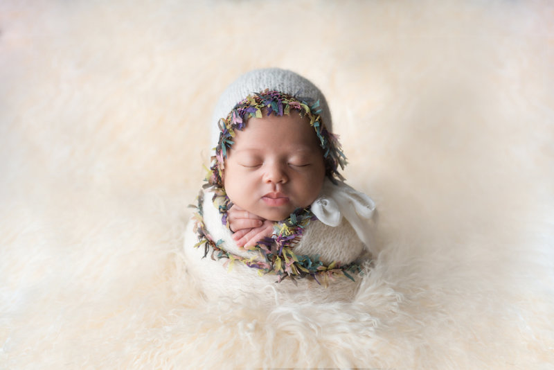 Newborn swaddled and posed on flokati rug during newborn photo shoot.