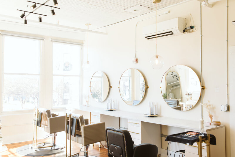 Bright and modern hair salon interior with round mirrors and styling chairs.