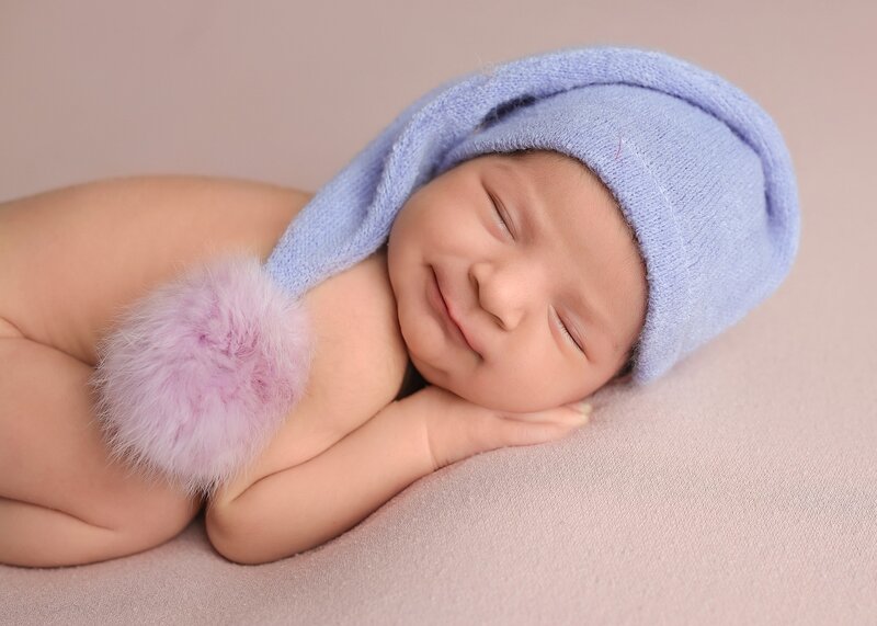 Sleeping newborn on pink blanket smiling