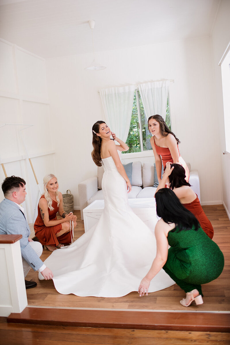 Bride assisted by her bridesmaids with her wedding dress