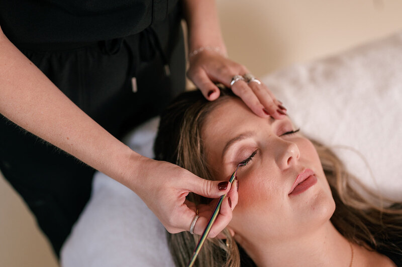 Woman laying down receiving an eyelash treatment from medspa practitioner