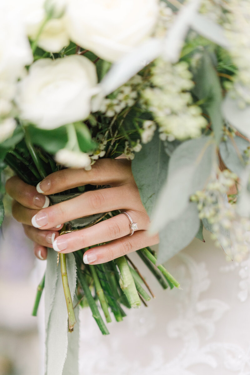 bride holding bouquet and showing off wedding ring