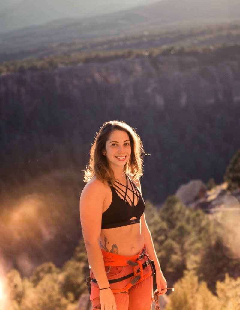 young woman stands in the sunset at Shelf Road, Colorado climbing area after a day sport climbing