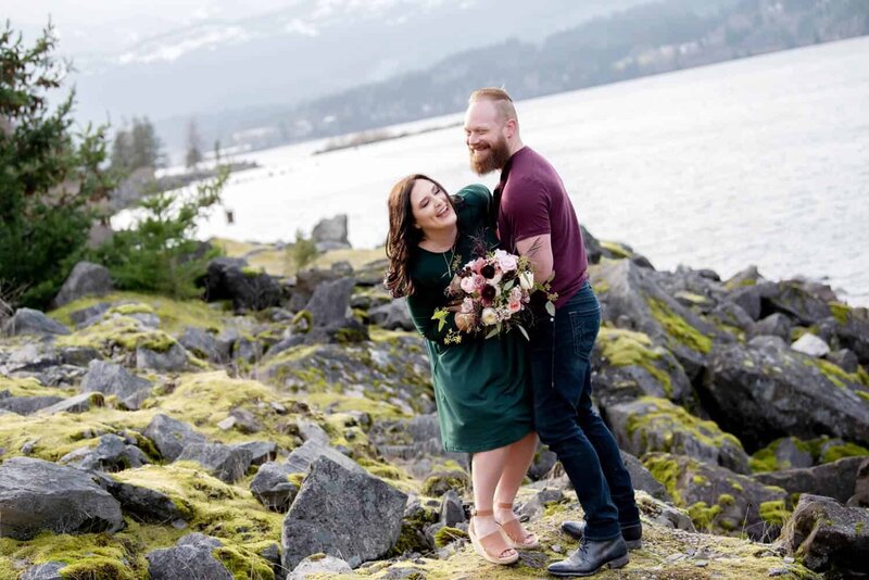 a man tickles a woman holding a pretty bouquet by flowers by alana overlooking the columbia river at Government Cove