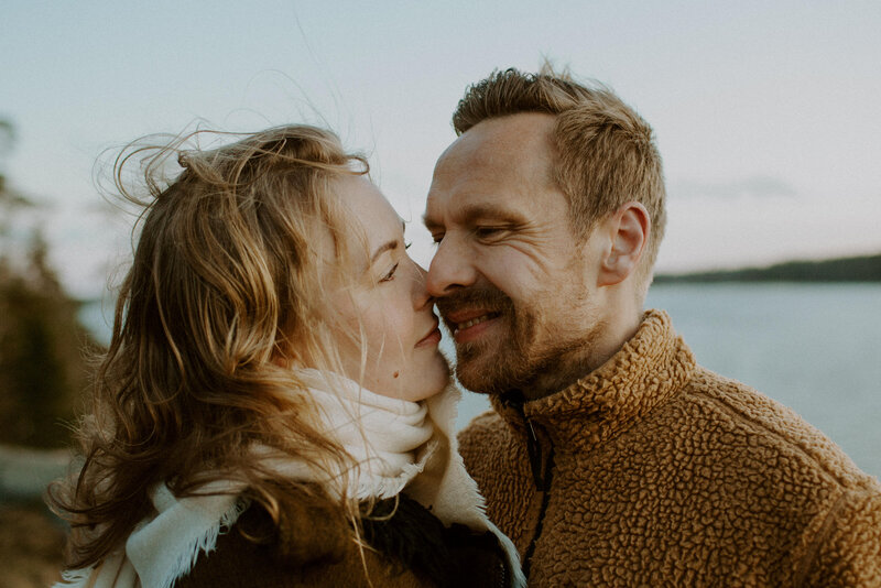 Kihlapari seisoo kasvot vastakkain hyvin lähekkäin ja hymyilevät Kivenlahdessa Espoossa