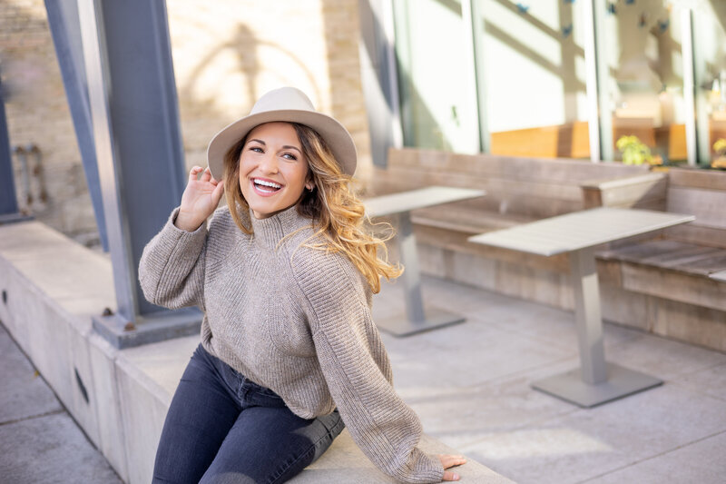 Smiling woman in hat sitting outside of coffeeshop