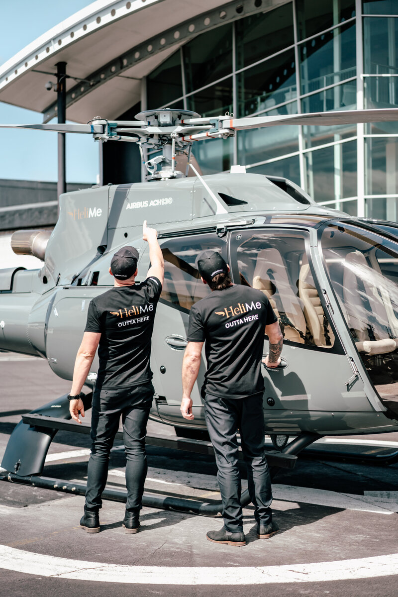 2 male pilots with the back towards the camera standing infront of a Luxury Airbus Helicopter looking up to the rotor blades - capture by Auckland Commercial Photographer Zanthe Vorsatz