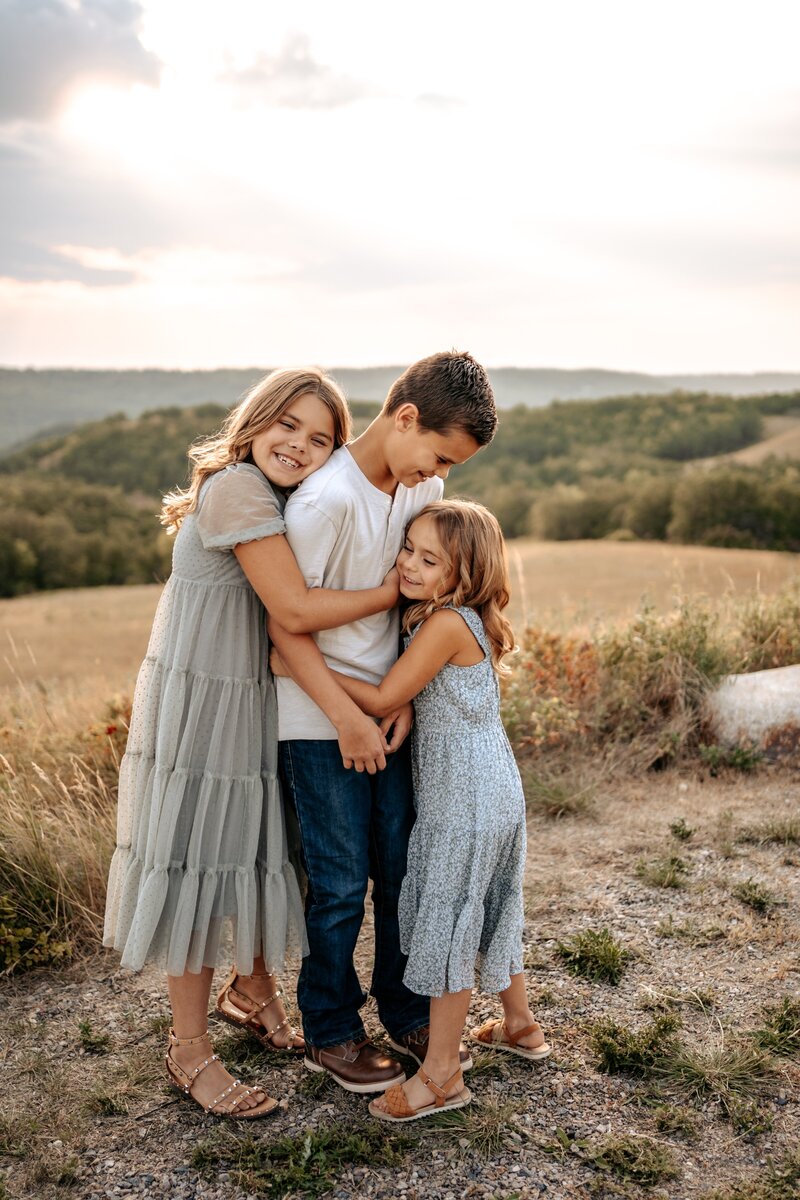 Brother and sisters hugging on top of a hill in North Dakota