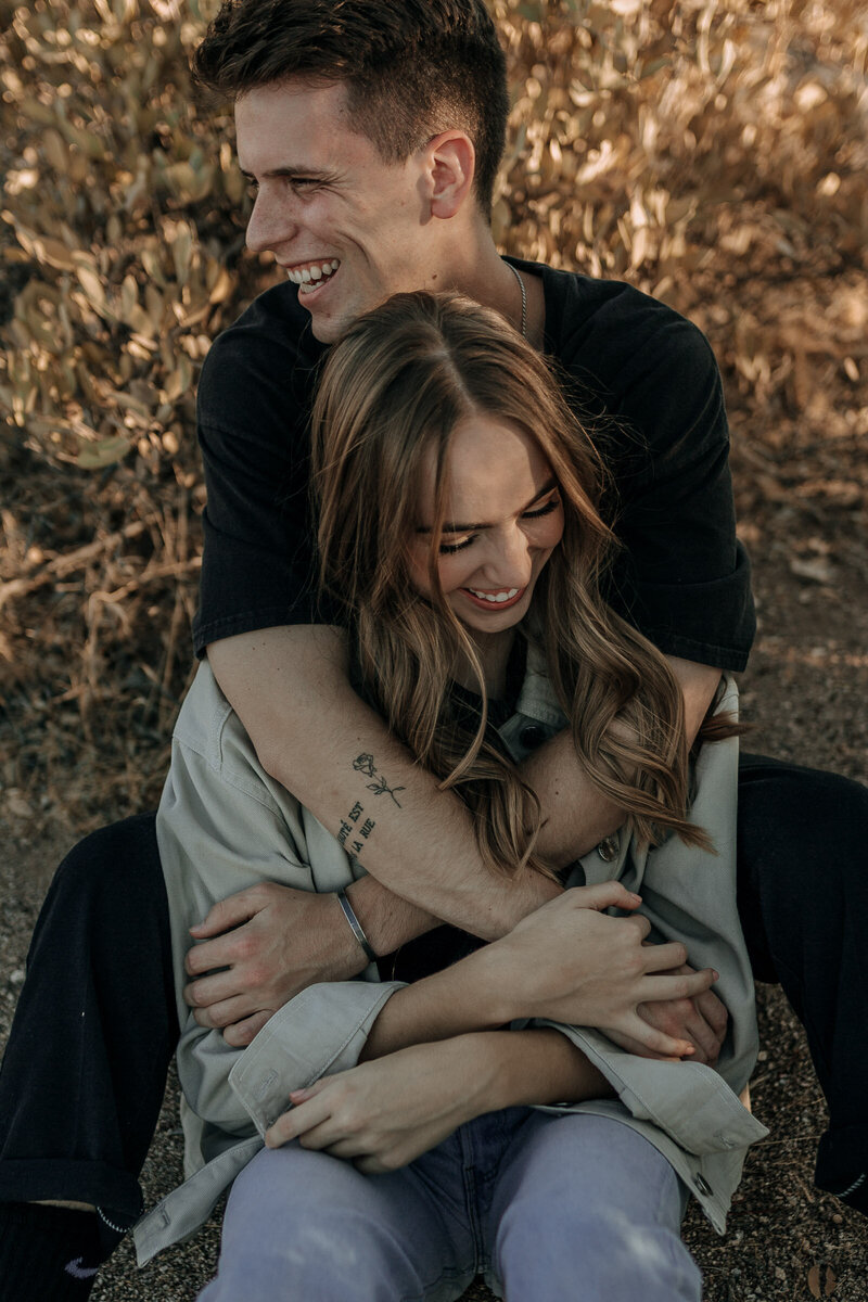 couple laughing engagement session sitting on a blanket