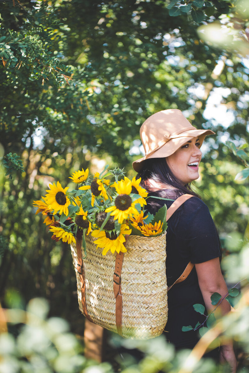 girl wearing a backpack full of yellow sunflowers