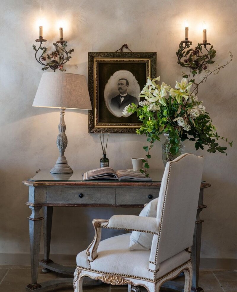 A refined and elegant writing desk at Borgo Santo Pietro with a large glass vase overflowing with white flowers and greenery