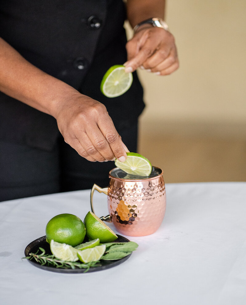 Chef adding limes to a copper mug