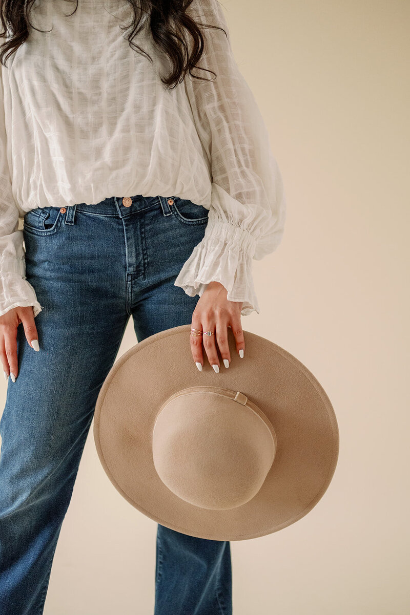Woman in jeans holding a hat