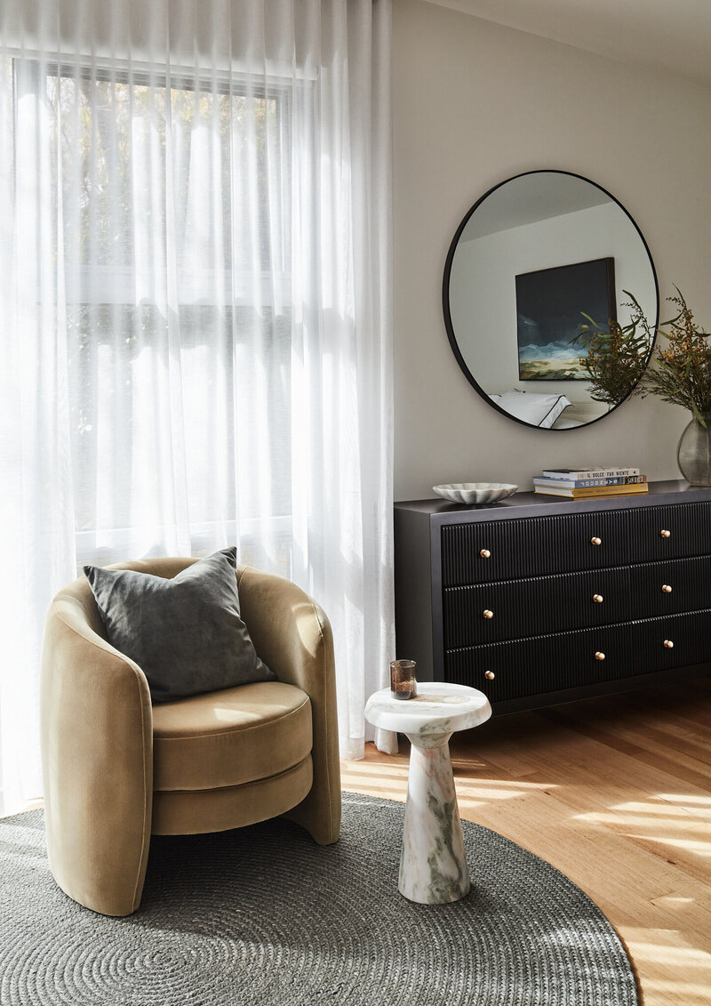 Modern turnkey interior design featuring armchair and sheer curtains in a light-filled living room.