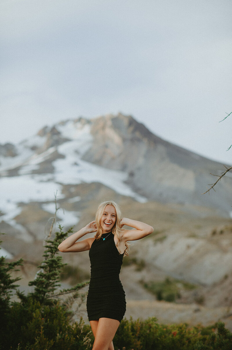 girl in black dress posing in front of mountain