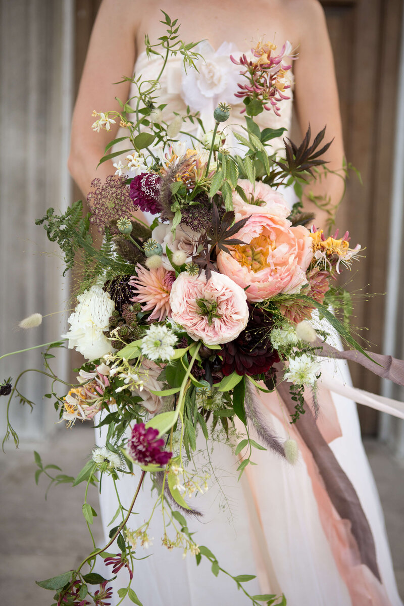 Large bridal bouquet of coral charm peony, nigella, jasmine, honeysuckle, grasses, poppy seed heads and dahilas