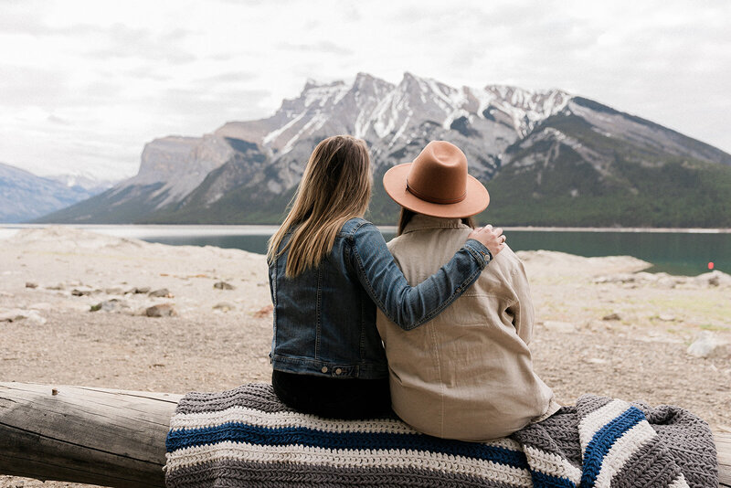 couple sitting with arms around each other looking at mountain