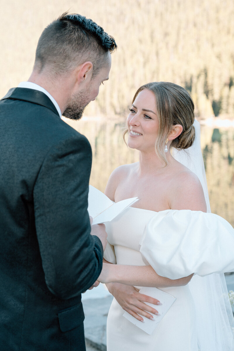 Intimate moment of bride and groom exchanging vows by the Lake Louise waterfront.