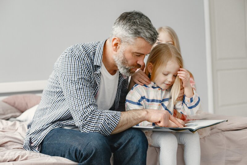 father working on homeschool lesson with daughters
