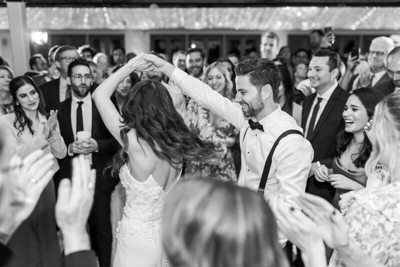 Groom spins his bride as guests dance around them during wedding reception