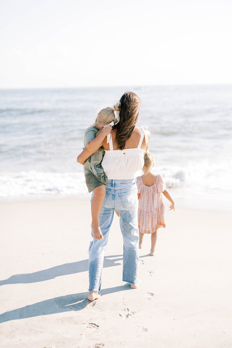 Mom walks with two daughters to the ocean on the Pennsylvania coast
