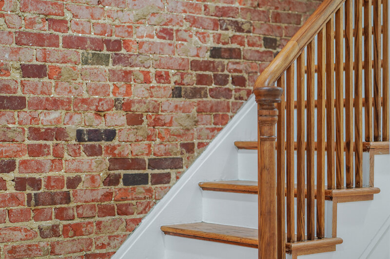Preserved brick wall and restored staircase. Captured by Home Visions Media for Bryce Enterprise's DC townhome project.