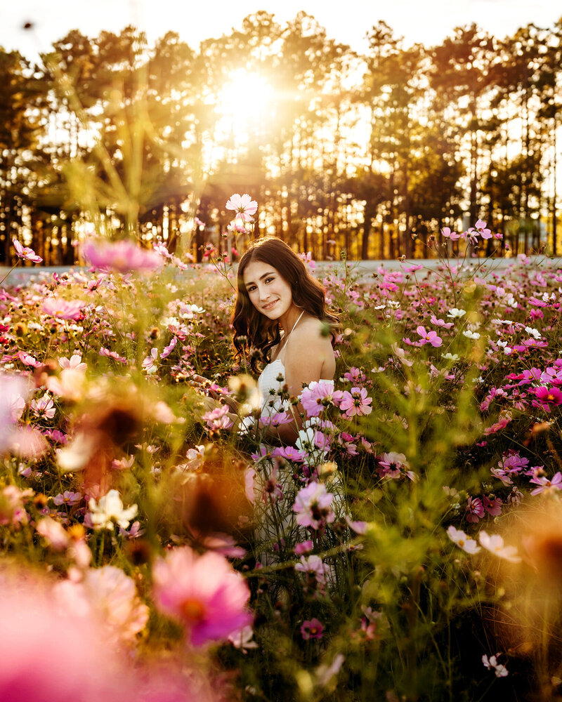 High school senior girl in a field of flowers at sunset in Fort Collins.