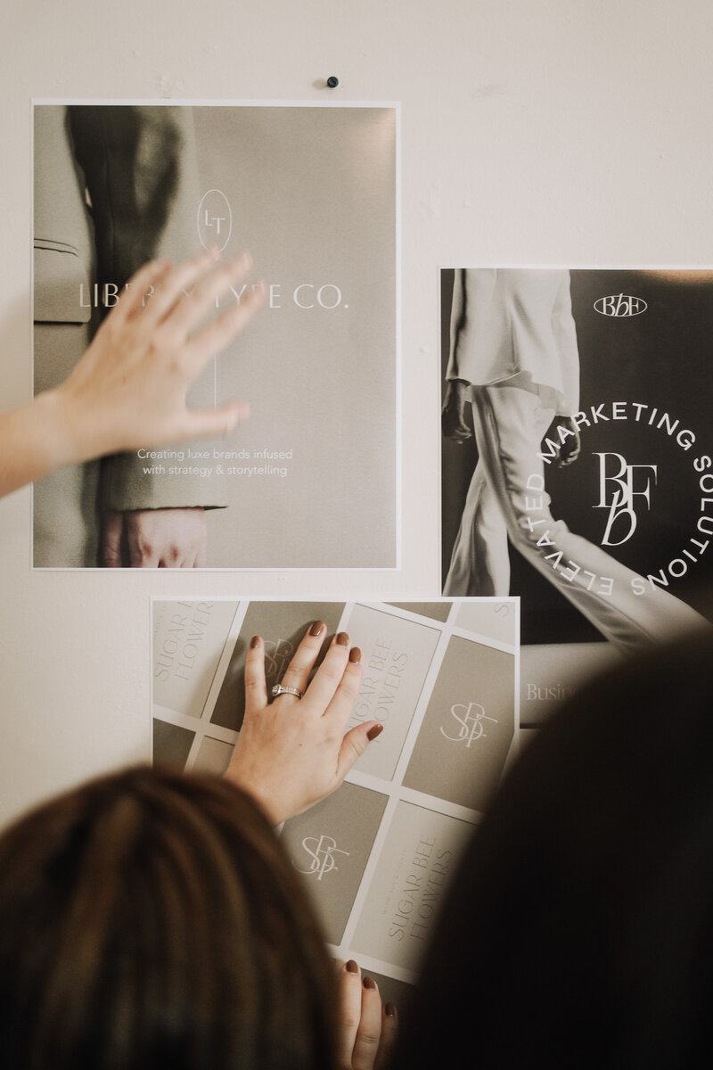 Woman pins logo mockups to bulletin board for presentation at brand design agency Liberty Type in Knoxville
