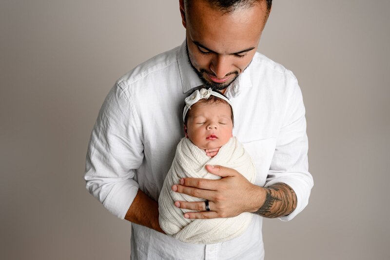 father snuggled his newborn daughter against his chest while looking down at her