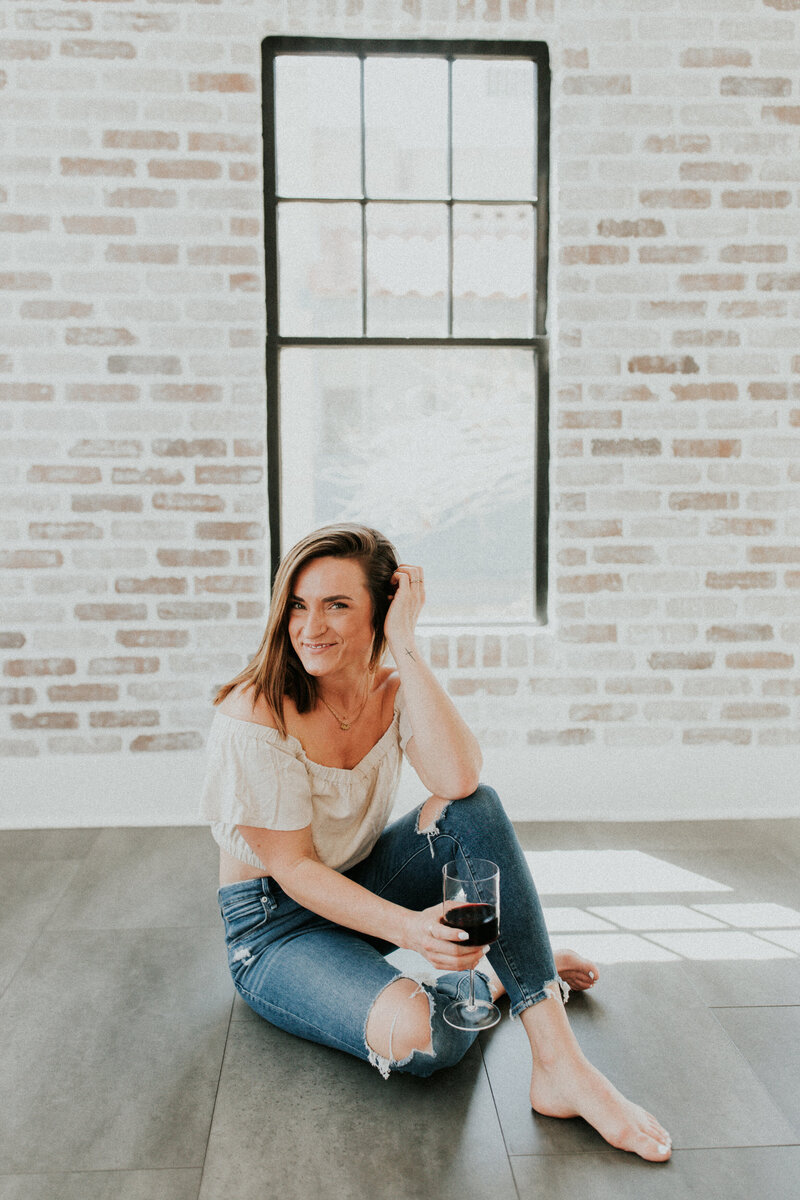 Missoula Montana photographer sits on the floor as she holds a wine glass.