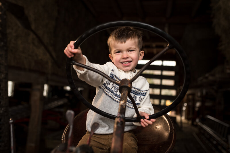 boy sitting on tractor smiling during a fun family photo shoot