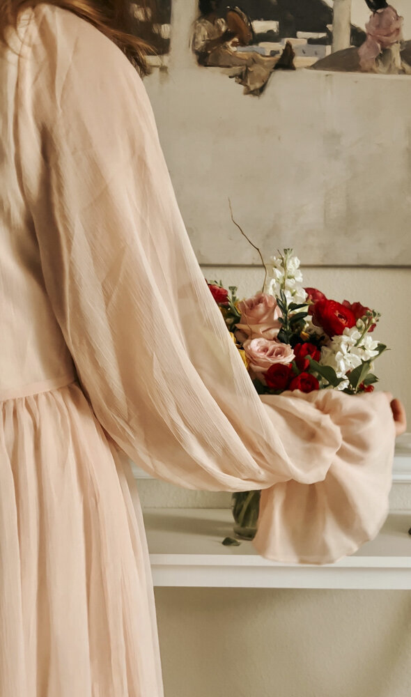 close up of a woman in a flowy dress holding a flower bouquet